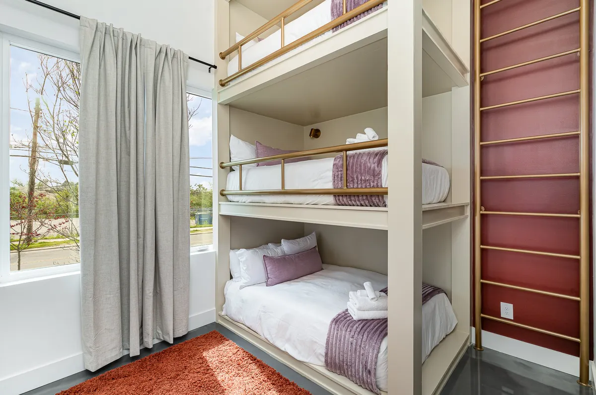 Here, a set of modern, playful bunk beds is shown, complete with privacy curtains and a sturdy ladder. The room is designed for both fun and function, and the arrangement encourages shared experiences and sleepover excitement for families or groups.