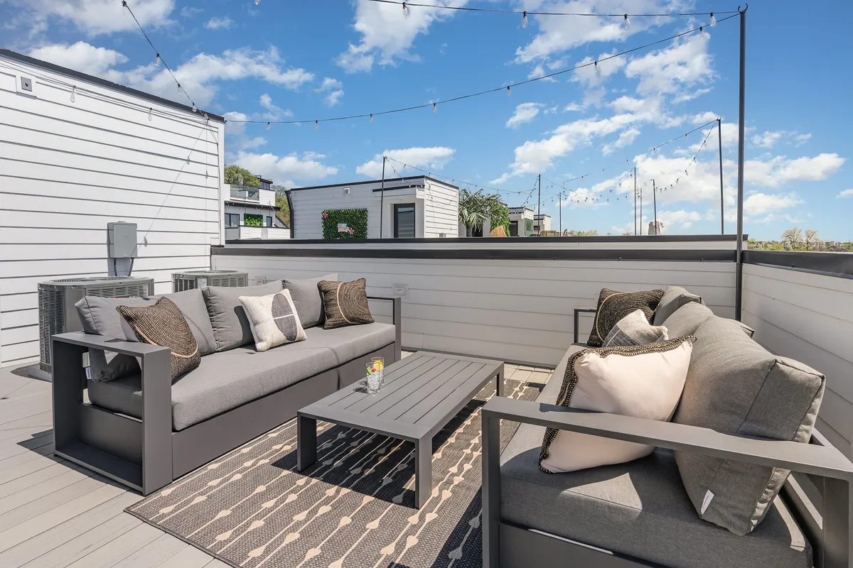 An inviting outdoor seating area featuring comfortable chairs with decorative cushions, a stylish coffee table, and string lights above, creating a casual, welcoming space for groups to gather and relax. The area is ideal for families or friends to share stories, enjoy evening conversations, or play games under the stars.