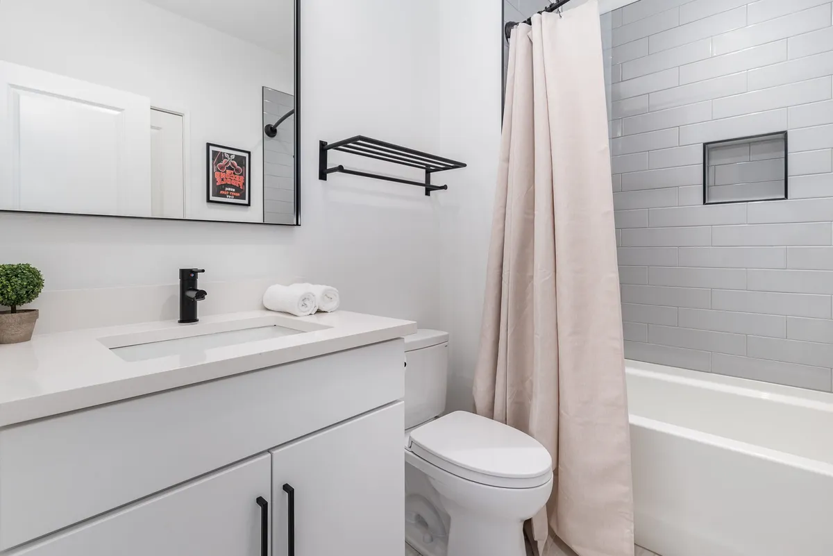 A spa-inspired bathroom is highlighted with a stylish vanity, large mirror, walk-in shower, and plush towels. The setting is bright, fresh, and evokes a soothing, luxurious atmosphere, ideal for personal grooming and relaxation.